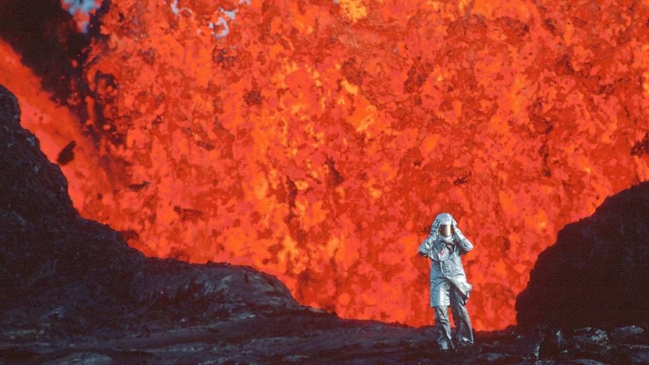 a person in a fire proof suit by a volcano